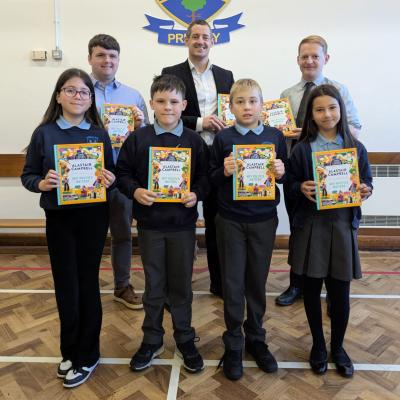 Pinsent Masons’ Senior Associate Matthew McMurray (back row, centre) presents copies of Alastair Campbell’s ‘Why Politics Matters’ book to pupils at Dunclug Primary School. They are joined by school principal Alastair Beacom (R) and teacher Scott Marcus.